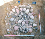 Overview of the well with square pit and inner lifting hole, filled with stones